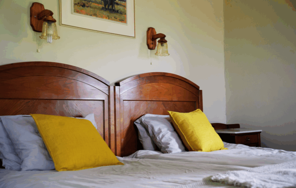 Zimmer mit Holzbetten und gelben Kissen – Jagdfarm Otjimbuku Hochfeld Namibia