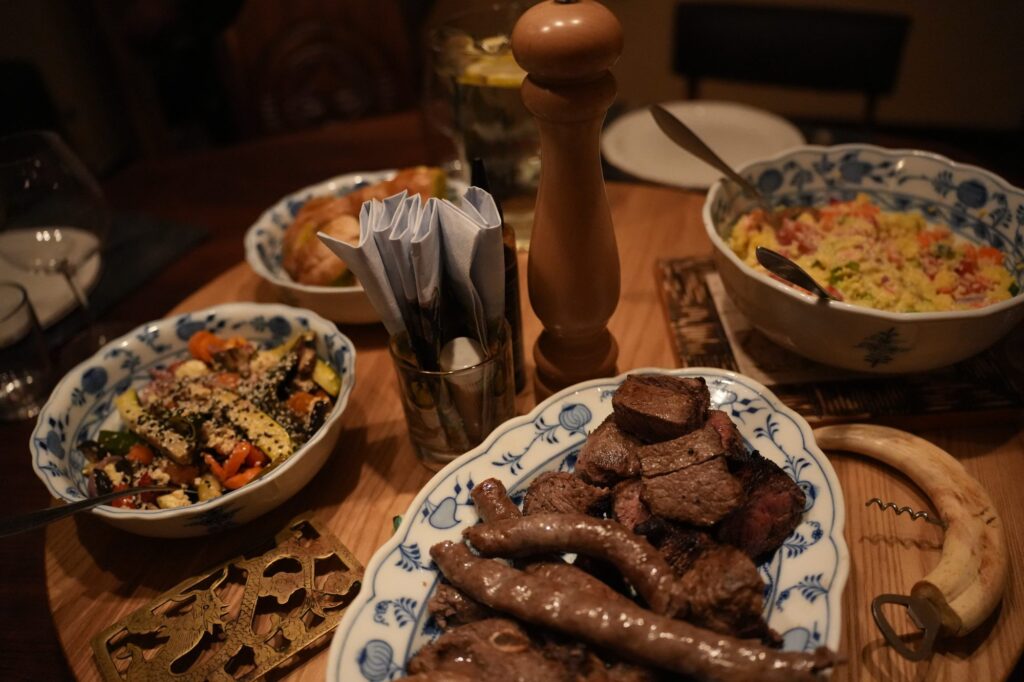 Rustikales Abendessen mit Wildfleisch, Gemüse und traditionellen Beilagen – kulinarisches Erlebnis auf einer Jagdfarm in Namibia.