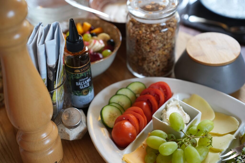 Frühstückstisch mit Müsli, frischem Obst und Trophäen im Hintergrund – ländlicher Charme und Safari-Ambiente.
