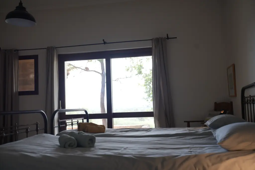 Helles Gästezimmer mit Doppelbett, großen Fenstern und Blick ins Grüne in Namibia