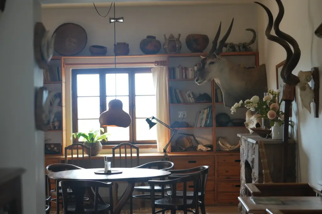 Traditionelles Wohnzimmer auf namibischer Jagdfarm mit Eland-Trophäe, Holzmöbeln und Bücherregal